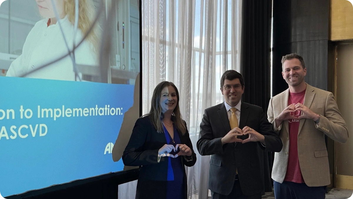Three LATTICE™ members making heart-shaped hand gestures beside the "Evidence Generation to Implementation" presentation screen
